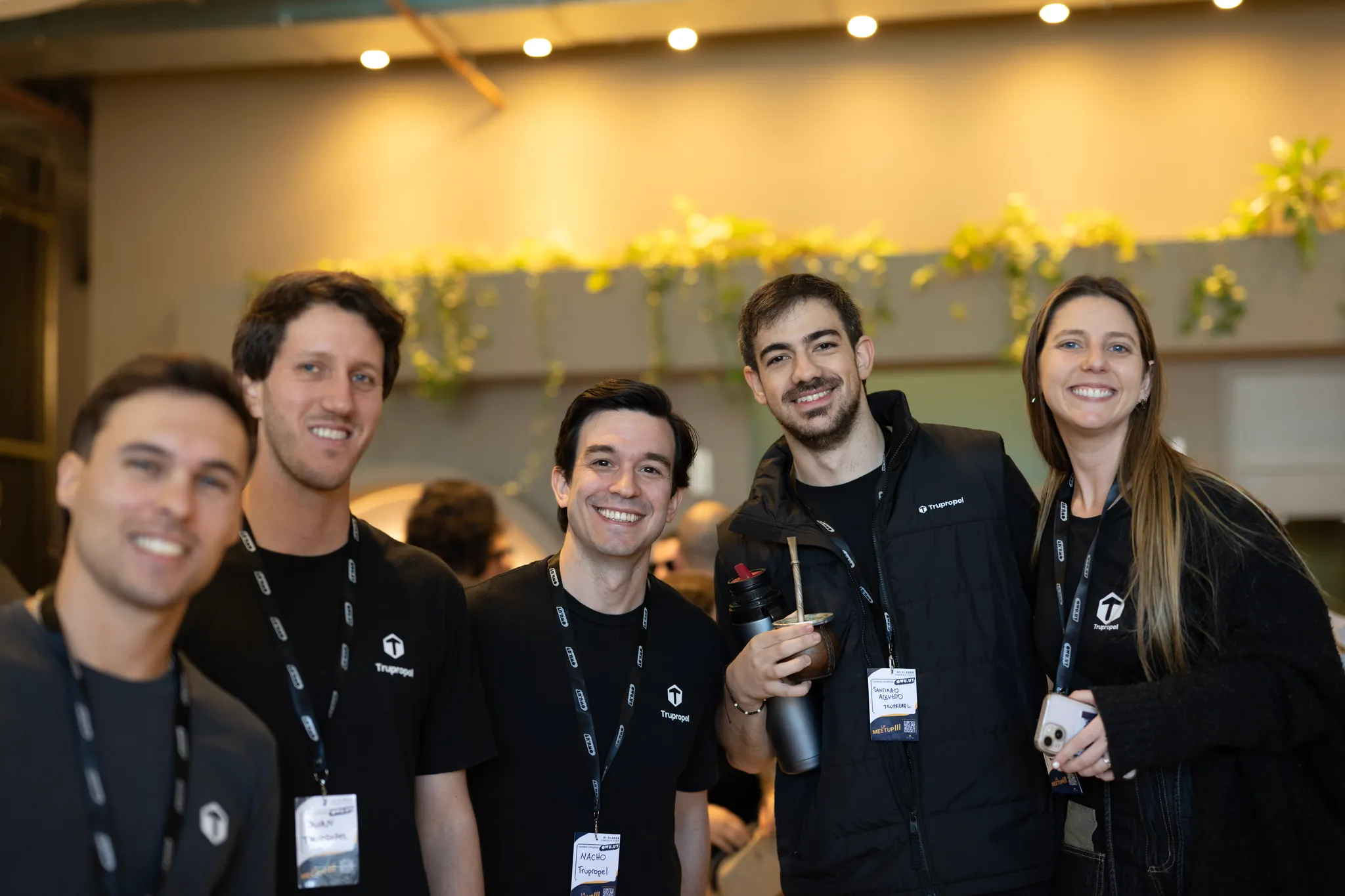 Cinco asistentes sonriendo juntos en el lobby