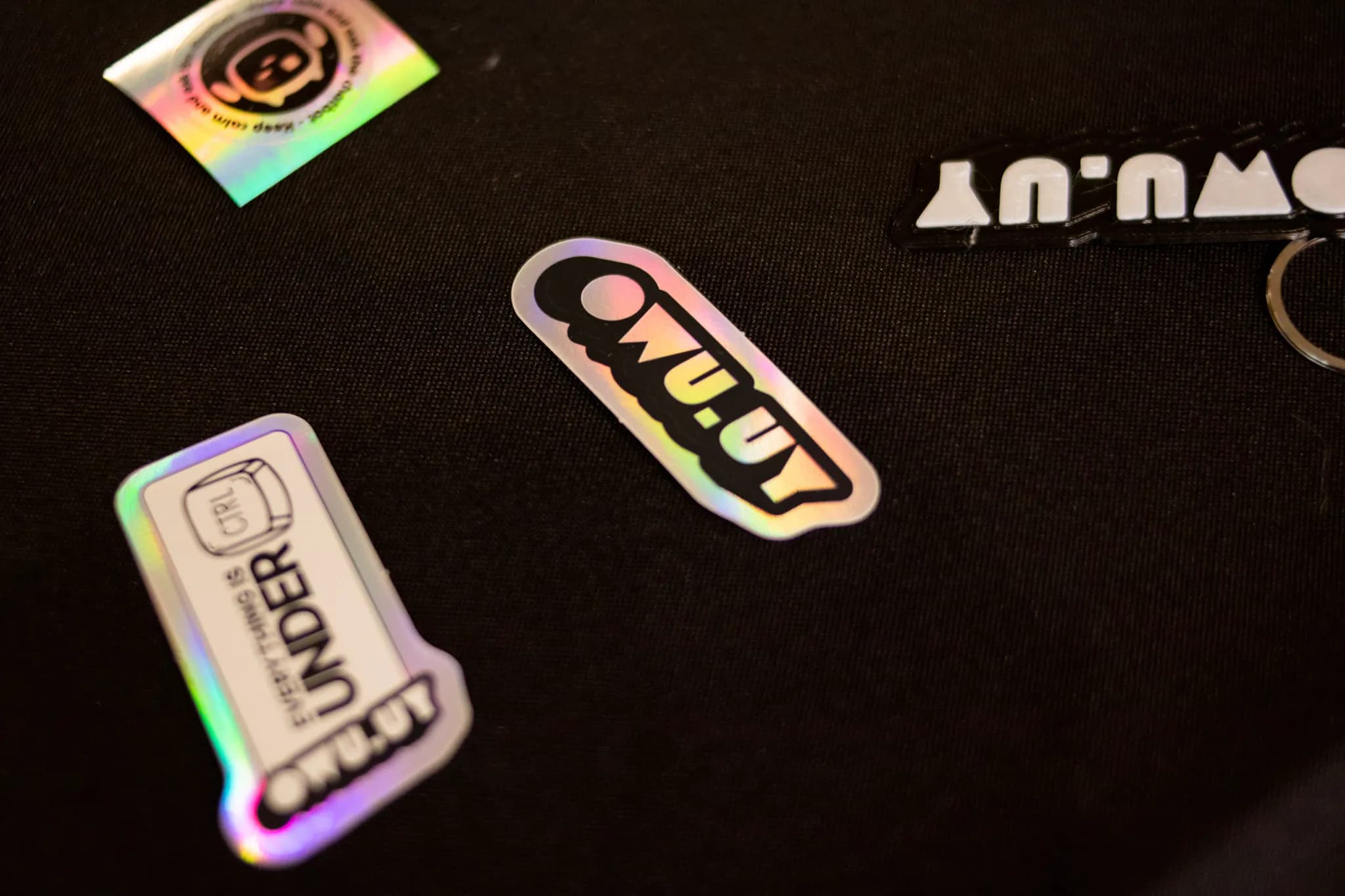 Stickers holográficos de OWU.UY sobre una mesa